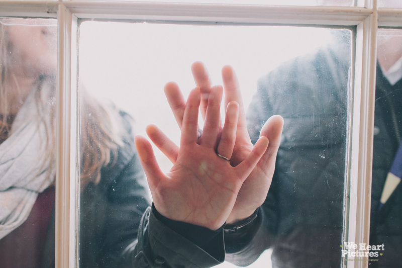 Hands on top of each other on a glass window.