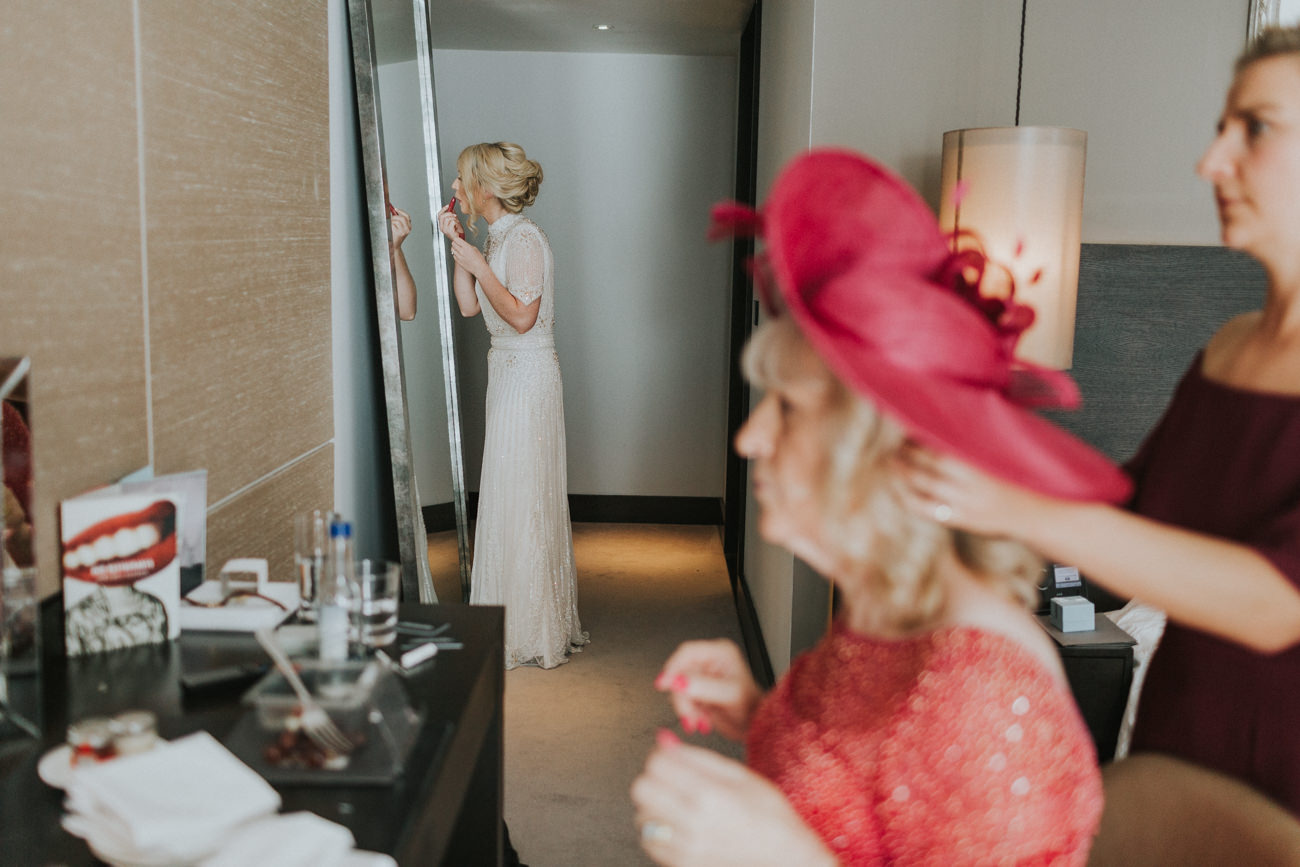 Bride in front of a mirror applying make up.