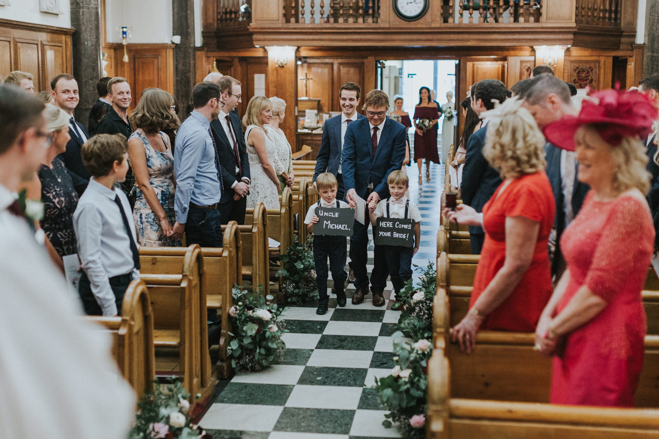 Page boys waking the aisles at St Mary Moorfields Church with signs for the groom. 