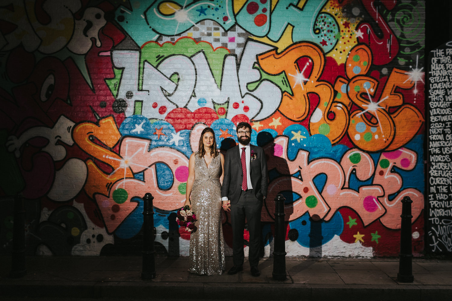 Bride and groom in front of street art in Shoreditch London.