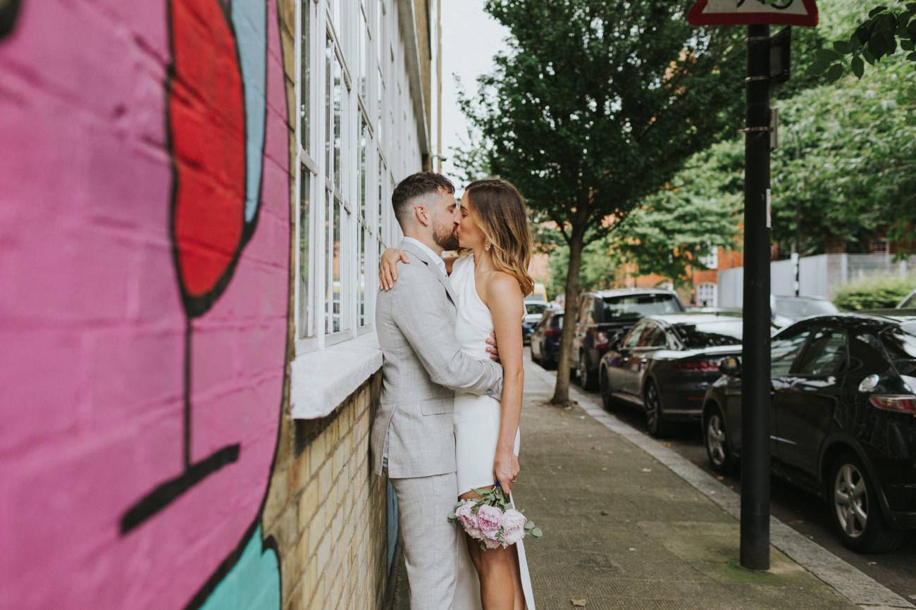 Bride and Groom kissing in front of street art in Shoreditch London