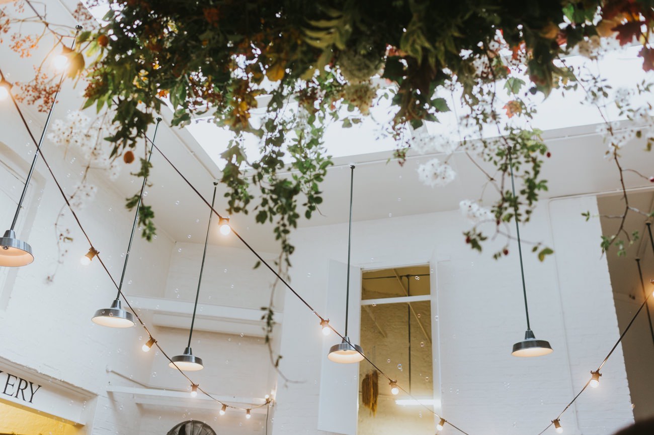 Small room wedding with draped florals and festoon lighting